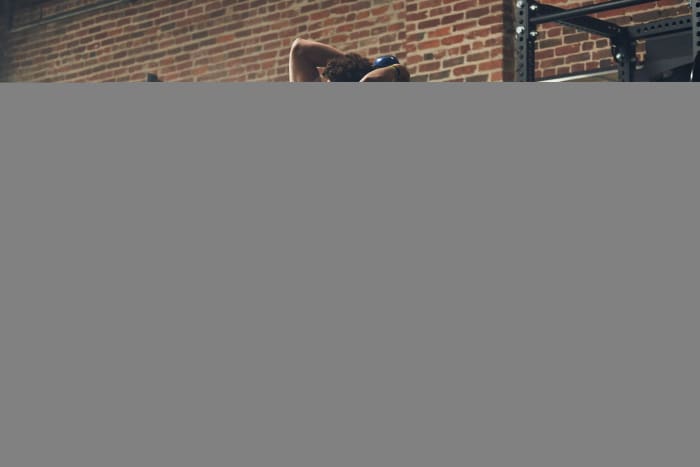 Patrick Mahomes lifts weights in white and red adidas training shoes.